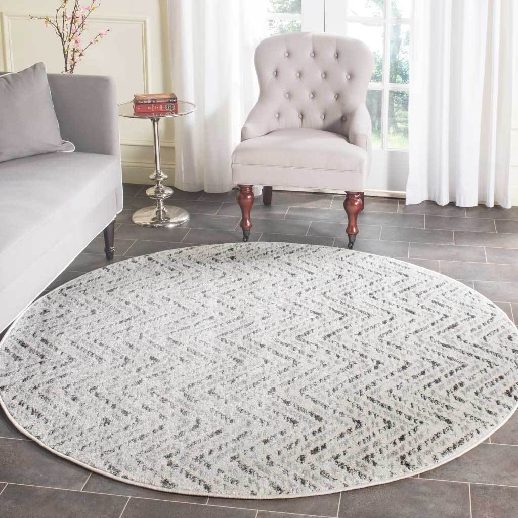 Round ivory and charcoal rug adds soft texture and chevron pattern beneath living room seating