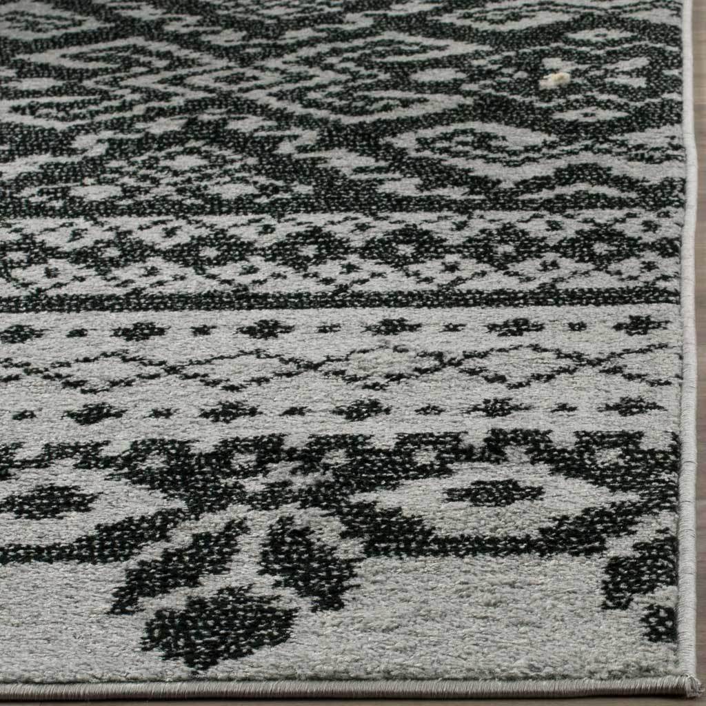 Dense black botanical motifs contrast with silver pile along a clean, bound edge.