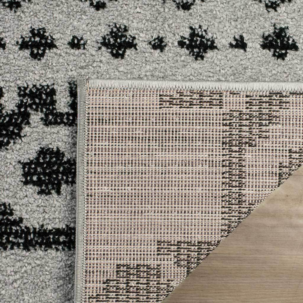 Tightly woven backing supports bold black-and-silver patterned pile with neat edge stitching.