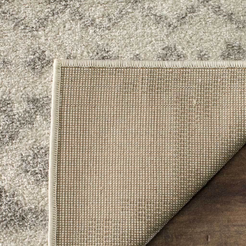 A finely woven underside complements the rug's ivory trim and soft silver pile.