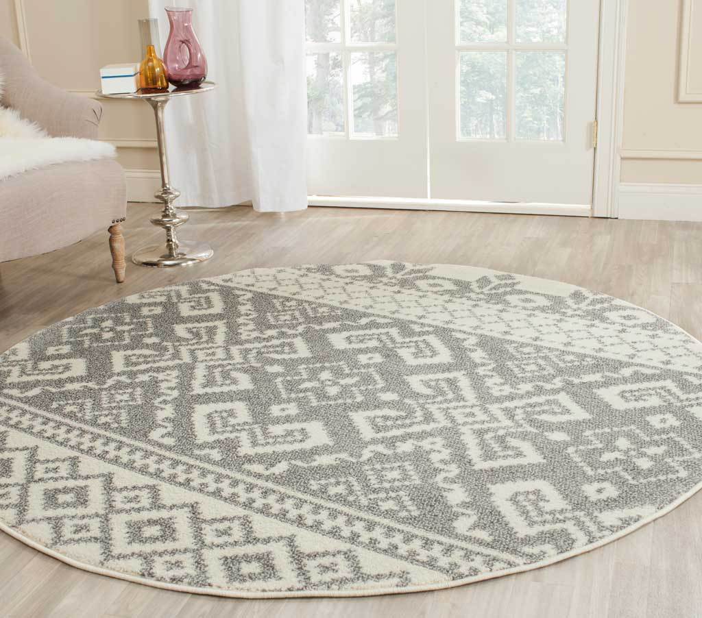 A round ivory and silver rug grounds the room with oversized geometric motifs and delicate borders.