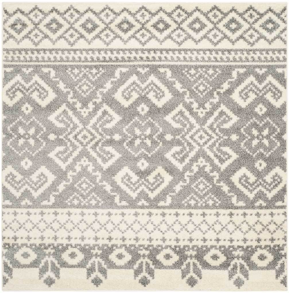 Square ivory and silver rug pairs symmetrical medallions with patterned floral and diamond borders.