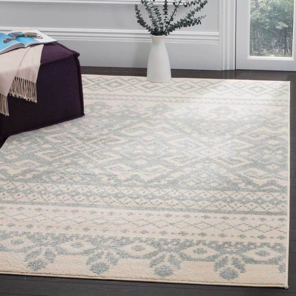 Delicate slate diamonds and floral borders bring airy color to an ivory area rug.