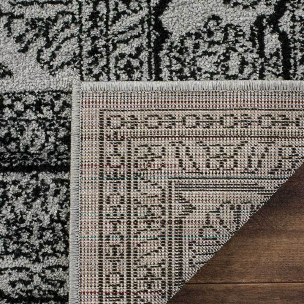 Turned-back corner shows patterned woven backing under the silver and black rug.