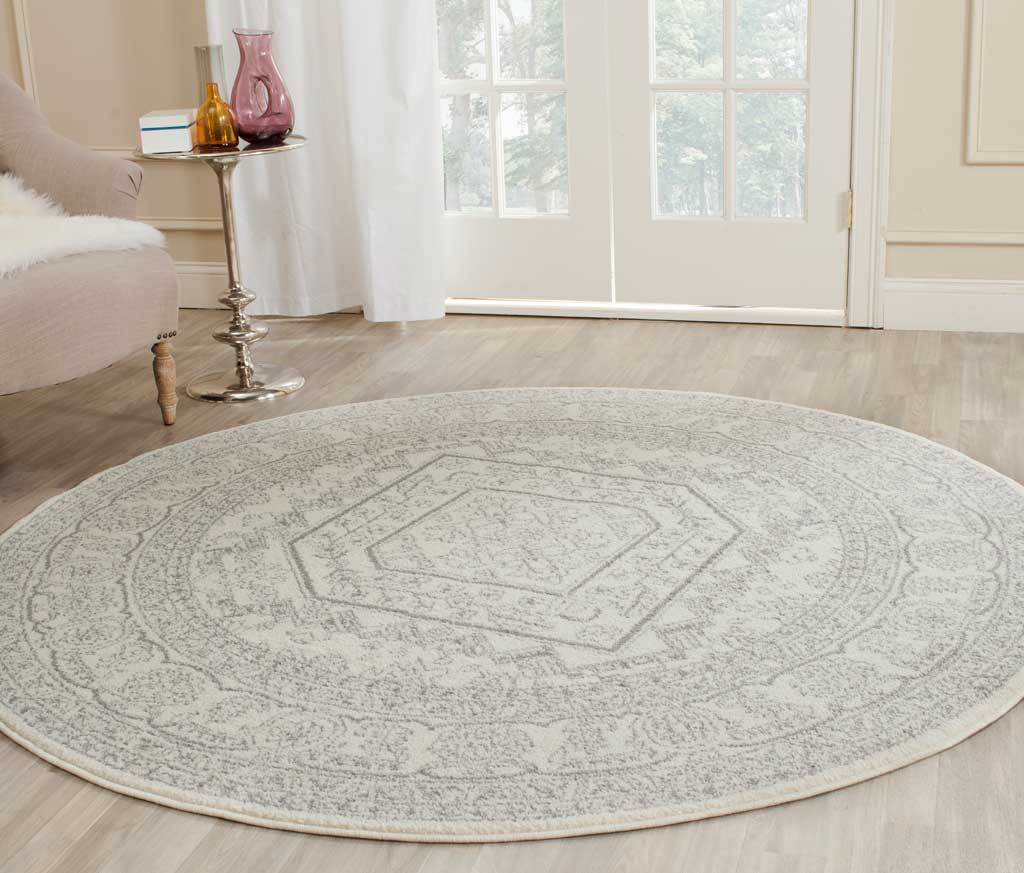 Softly faded ivory and silver round rug with a geometric center and floral border