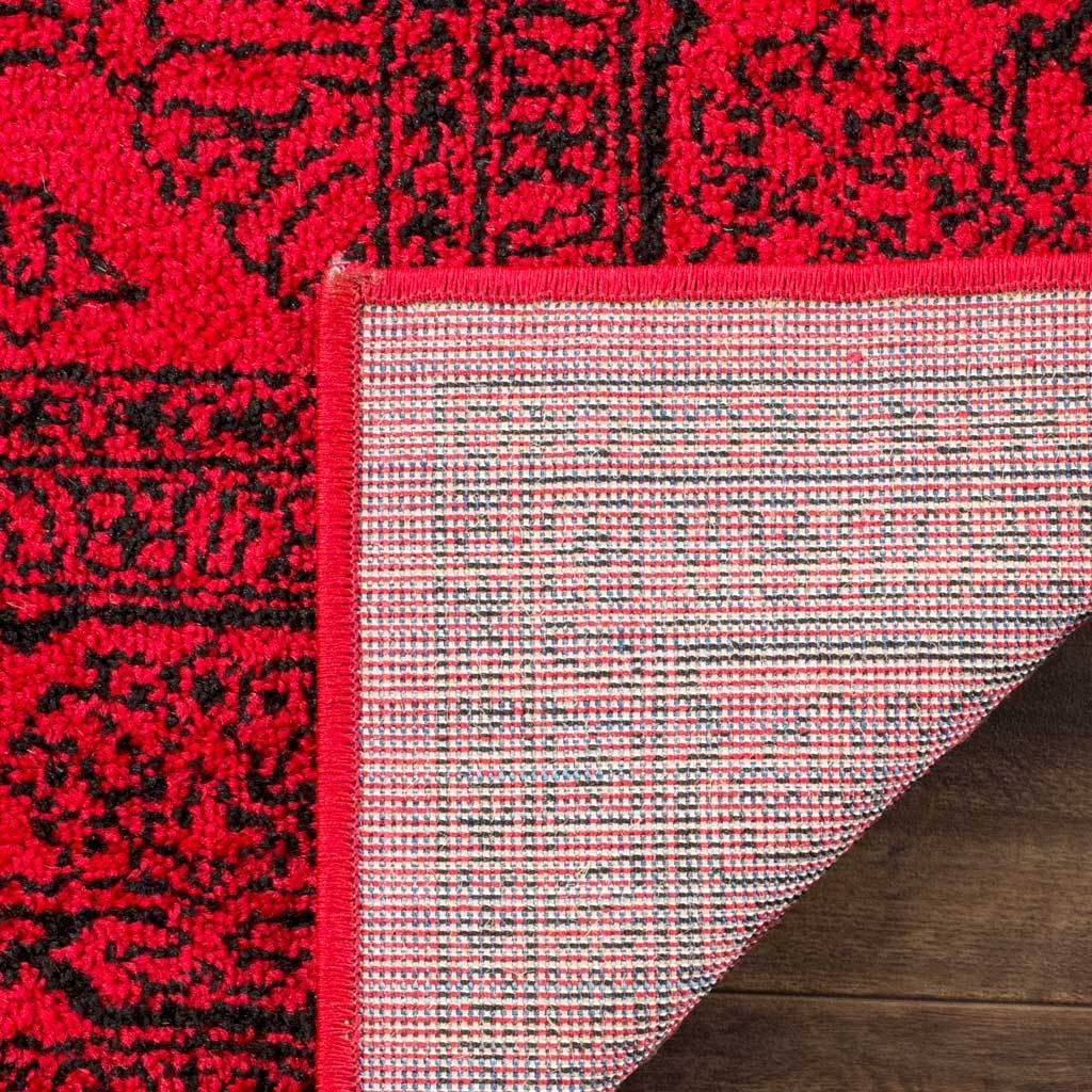 A folded red rug corner shows woven backing and a bright bound edge.