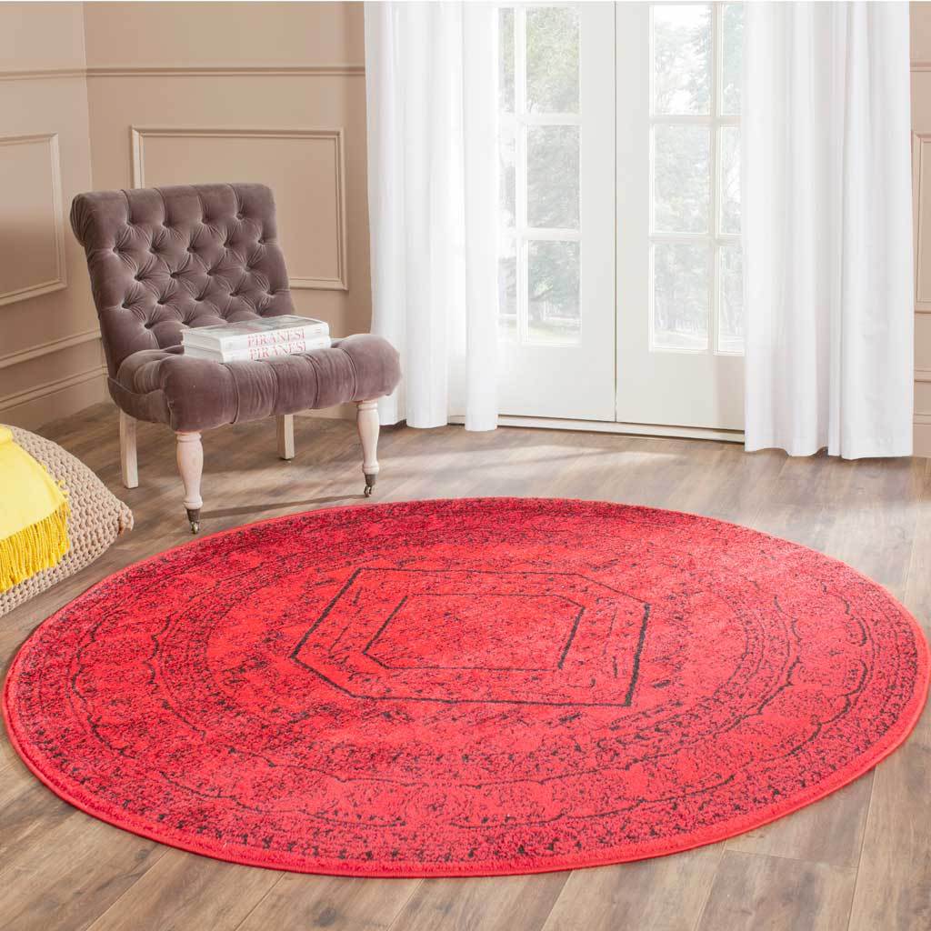 Red and black round rug anchors the room with striking color and ornate motifs