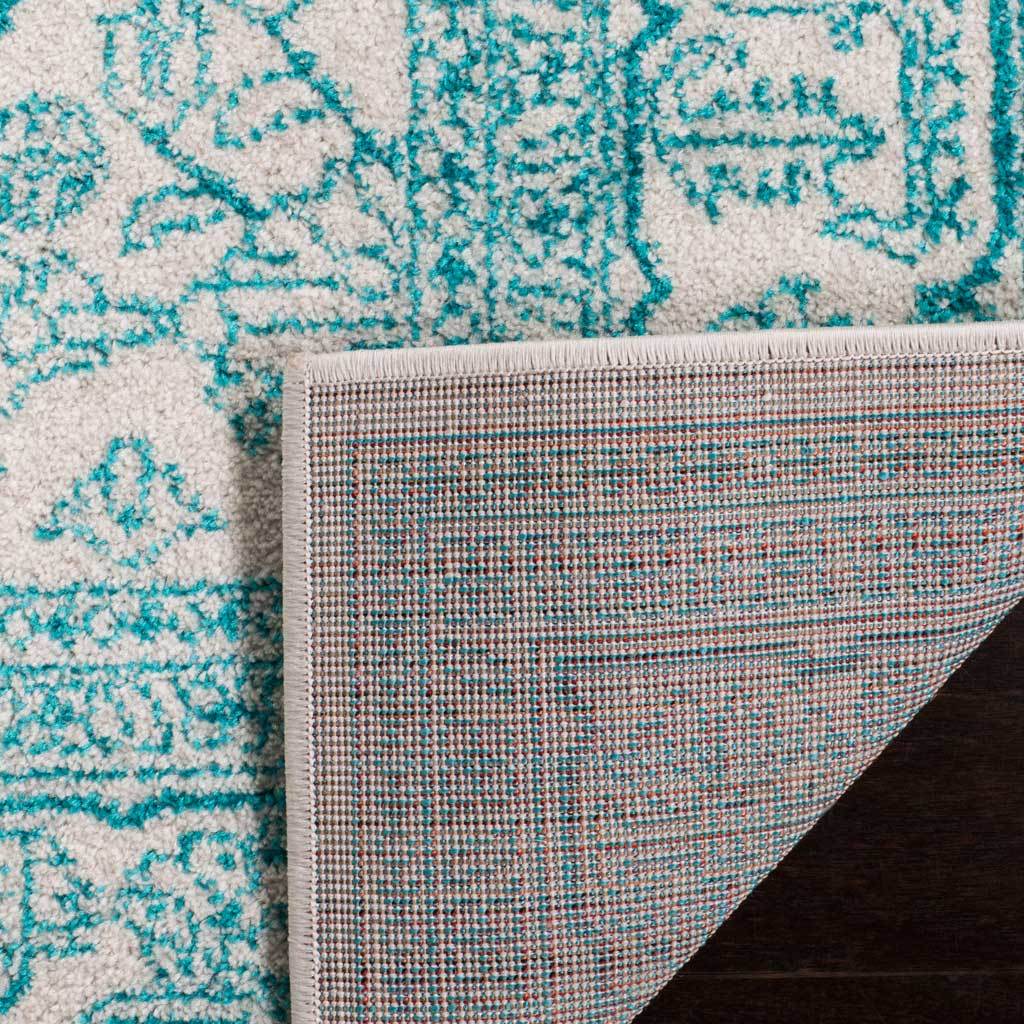 The turned rug corner shows tightly woven backing beneath teal and ivory pile.