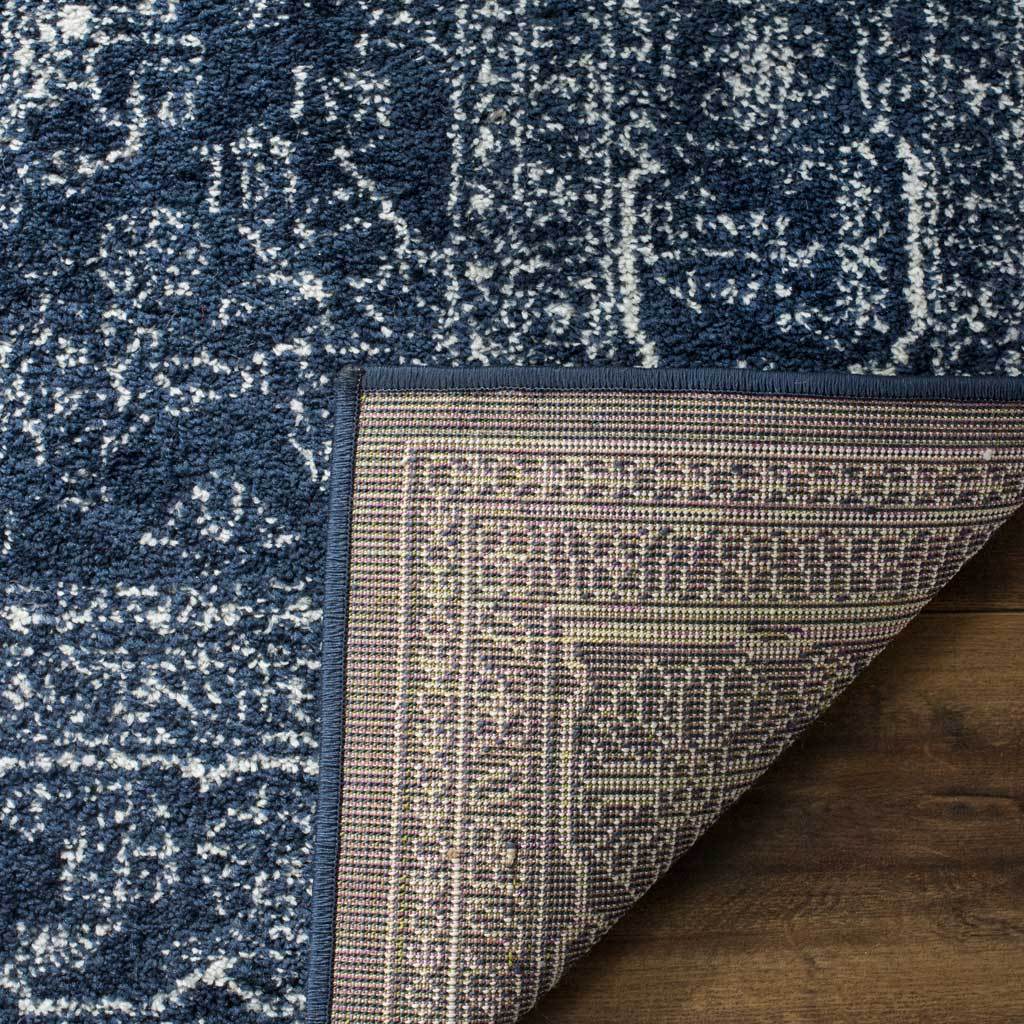 A turned-back corner reveals patterned woven backing beneath the navy and ivory pile.