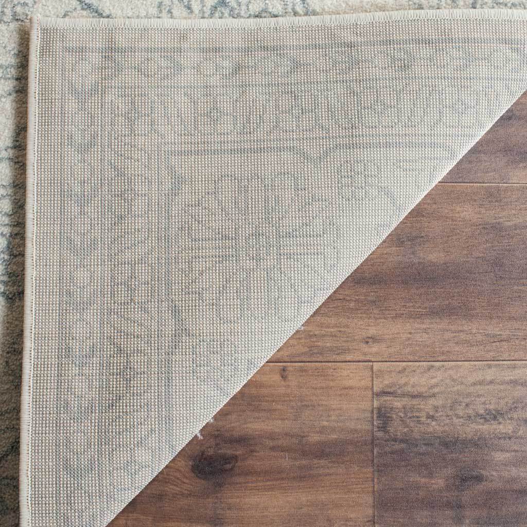 Turned-back rug corner reveals a tightly woven underside beneath pale patterned pile.