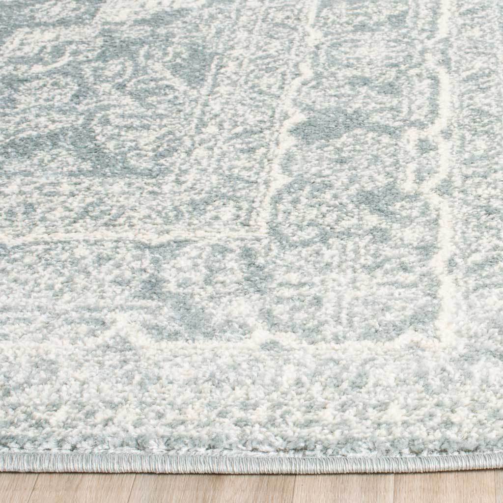 Soft ivory patterning meets pale slate pile at the rug's neatly bound edge.