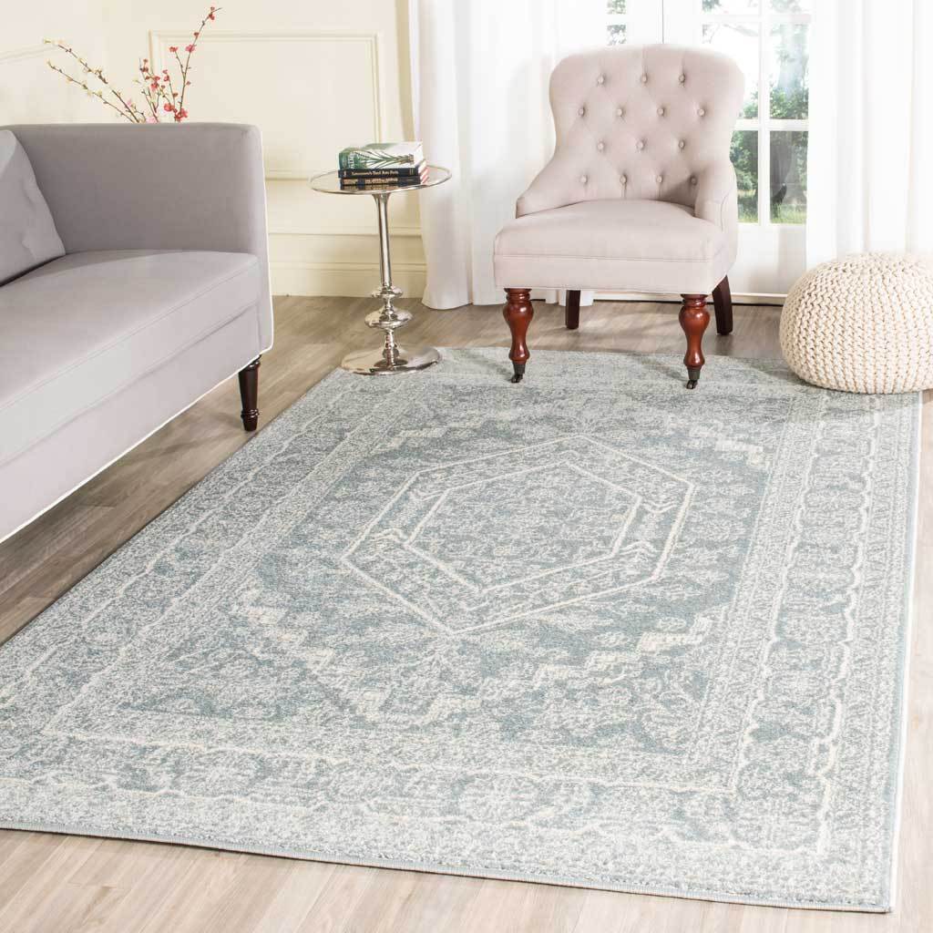 Muted slate and ivory floral rug lends vintage charm beneath light upholstered seating.