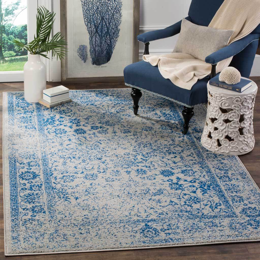 A gray-and-blue floral rug grounds a deep blue chair with a richly patterned border.