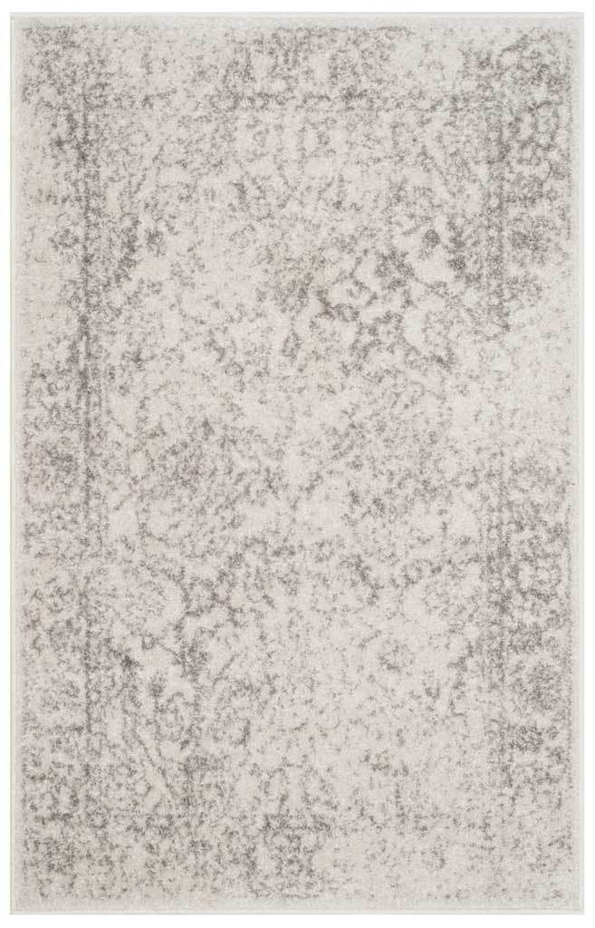 A small ivory accent rug carries a dense wash of distressed silver motifs.