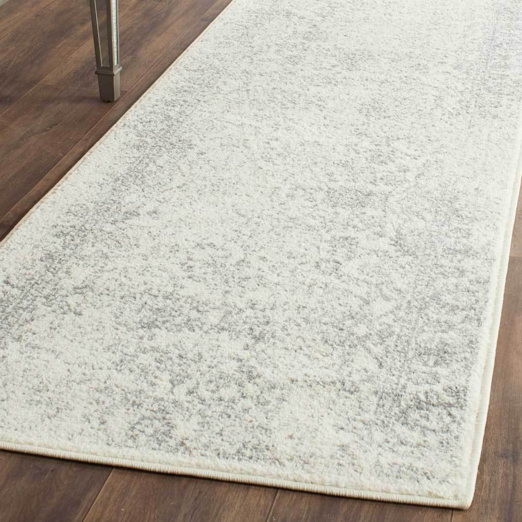 Silver flecks trace a faded pattern across an ivory runner rug with a neatly finished edge