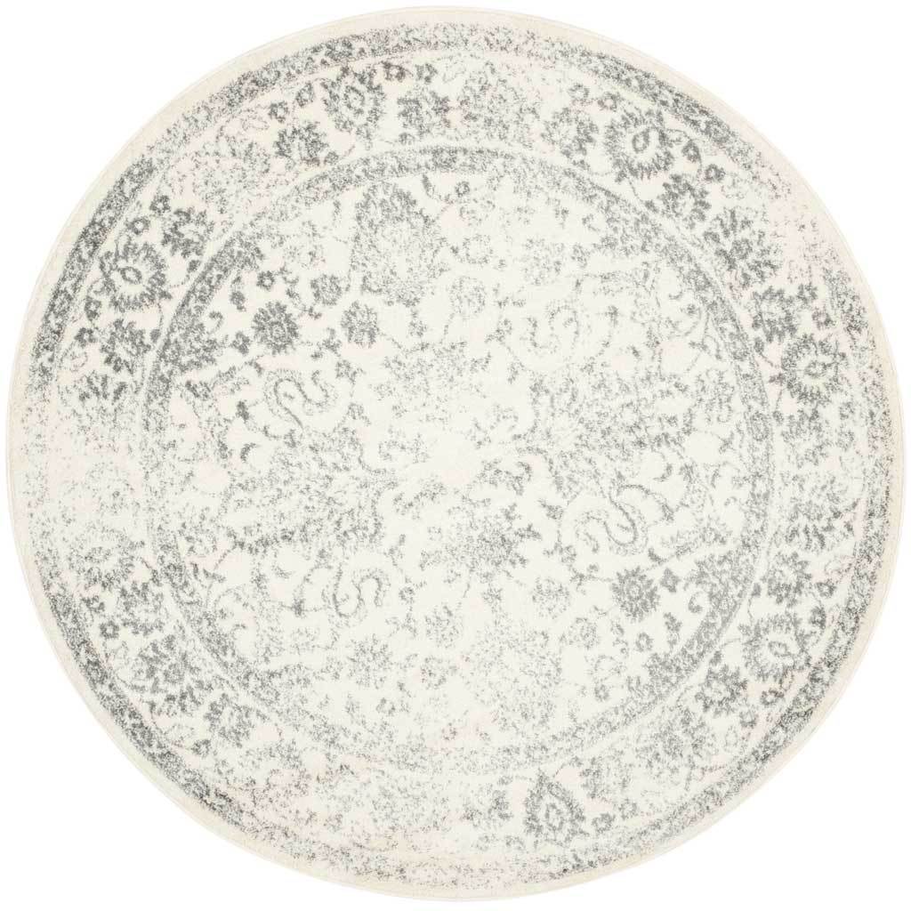 Faded silver vines and florals trace the center and border of this round ivory rug