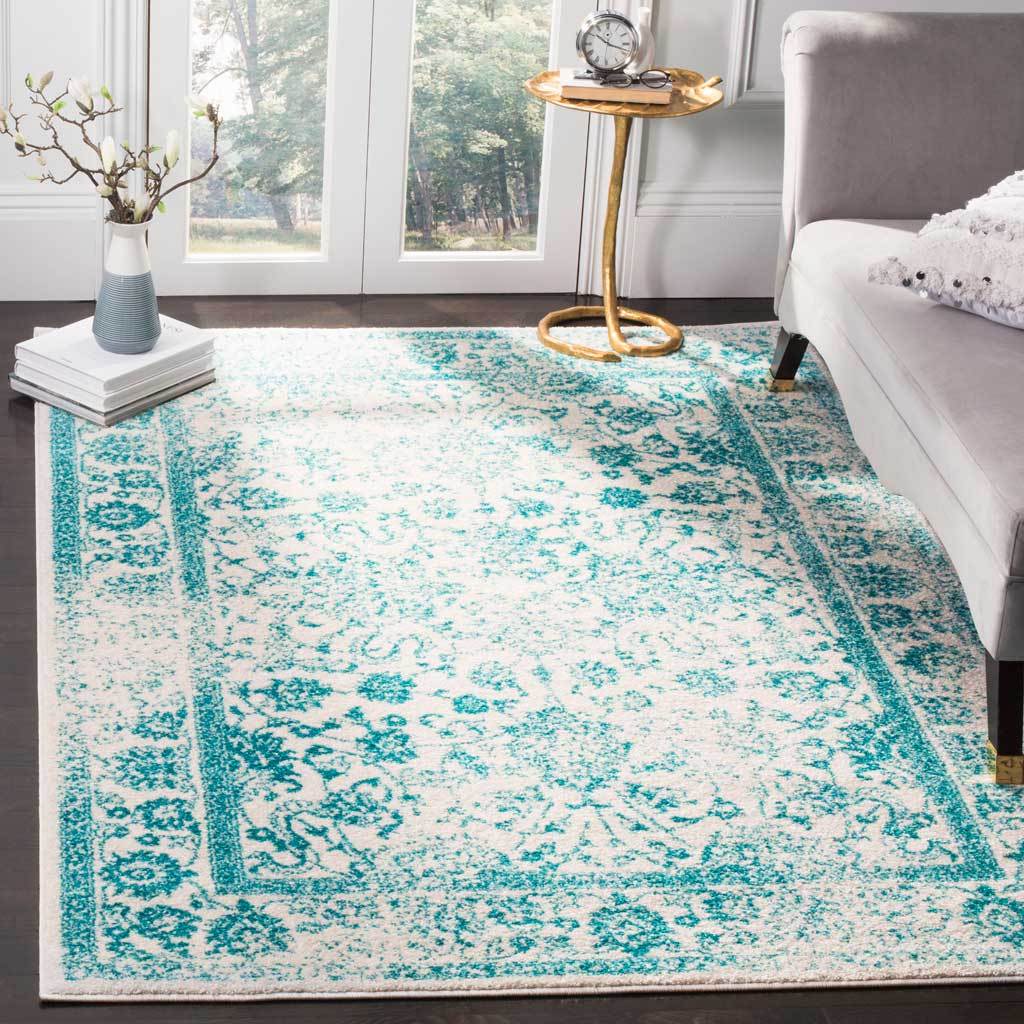 A bright teal-and-ivory rug anchors a sofa with scrolling florals and a framed center.