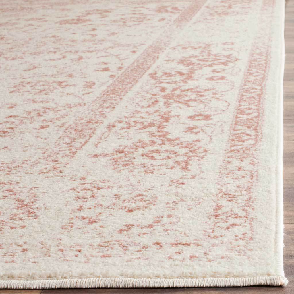 Soft rose scrolls trace across ivory pile above a tightly bound edge.