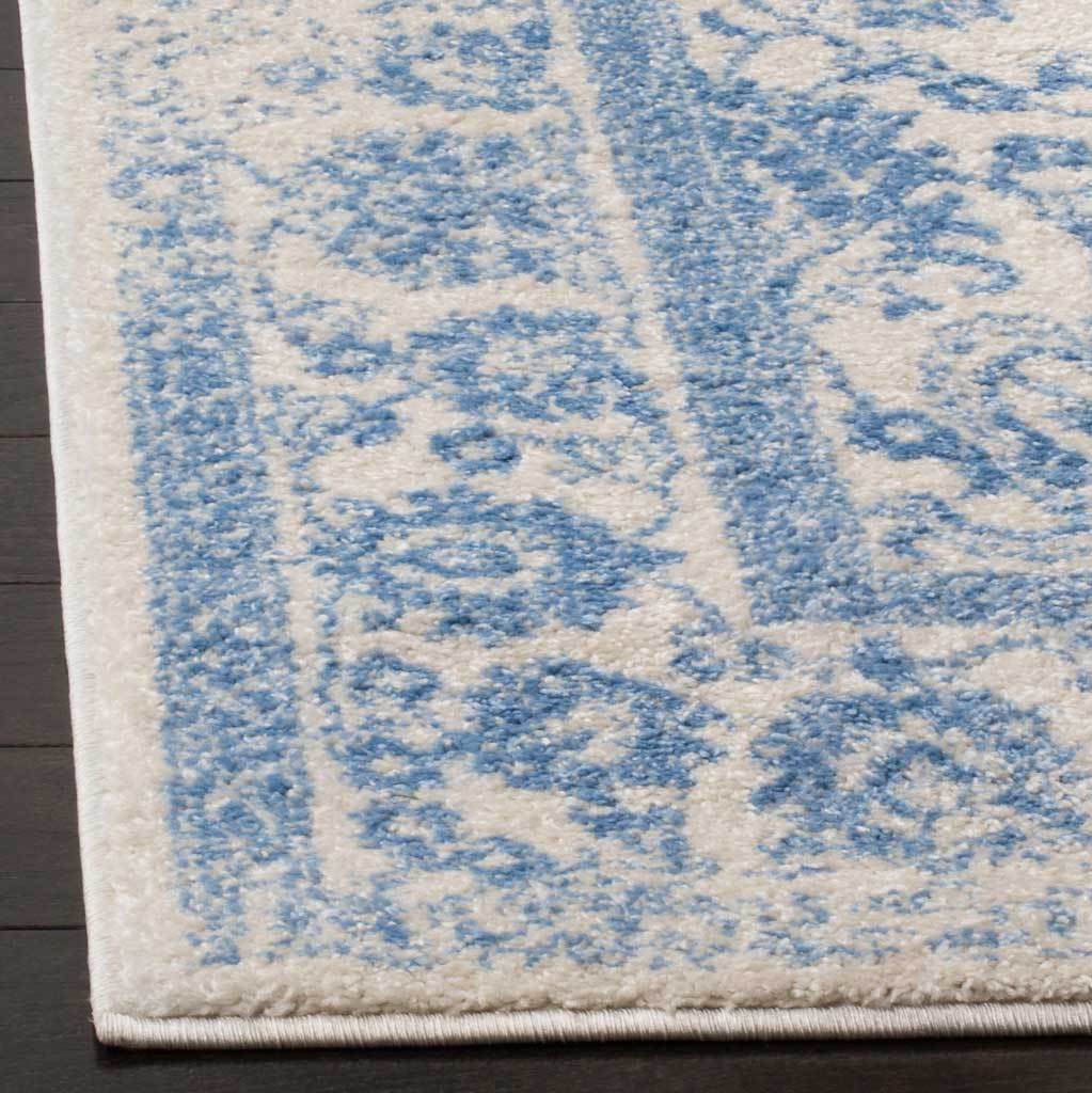 Light blue botanical motifs fade into soft ivory pile along a neatly finished edge.