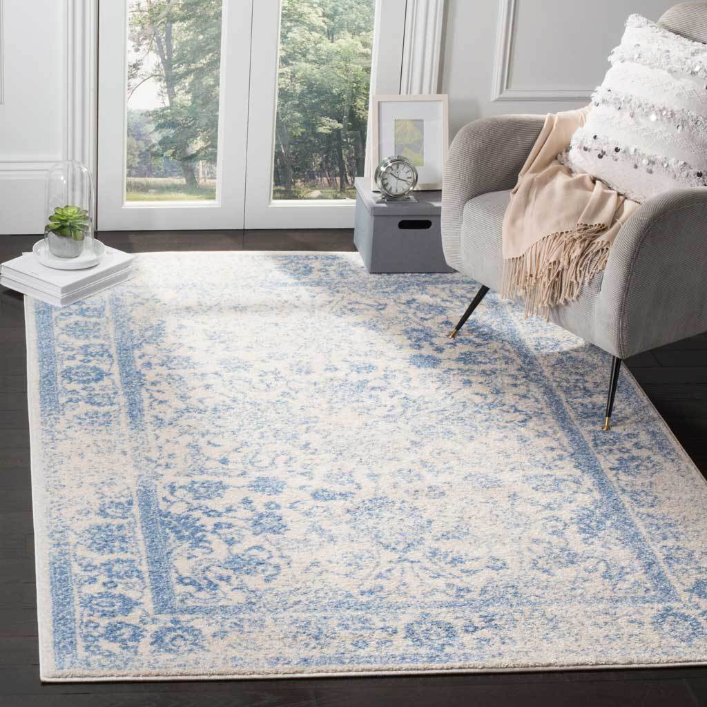 An ivory rug with pale blue scrollwork lends airy pattern beside a gray lounge chair.