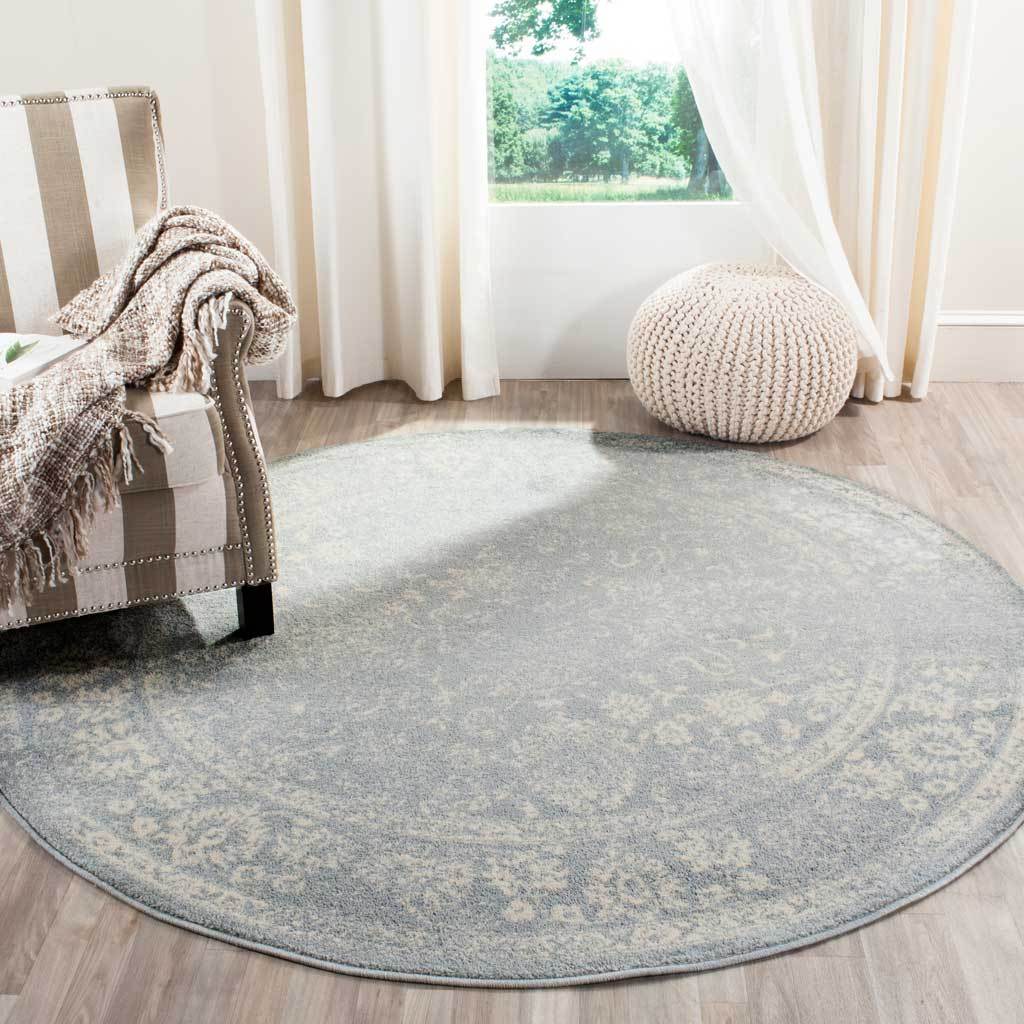 A slate and ivory round rug brings a softly worn floral design to the floor