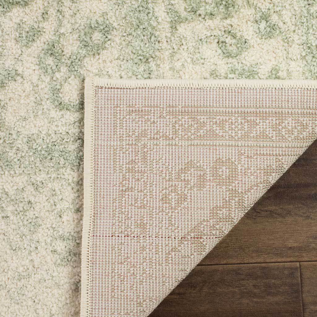 A folded corner reveals the woven reverse of this sage-and-ivory rug.