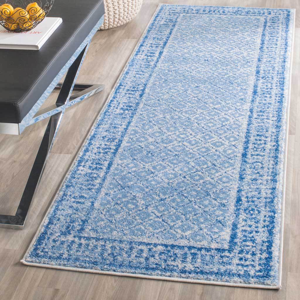 A slim blue and silver runner adds patterned warmth to a wood floor alongside modern furniture
