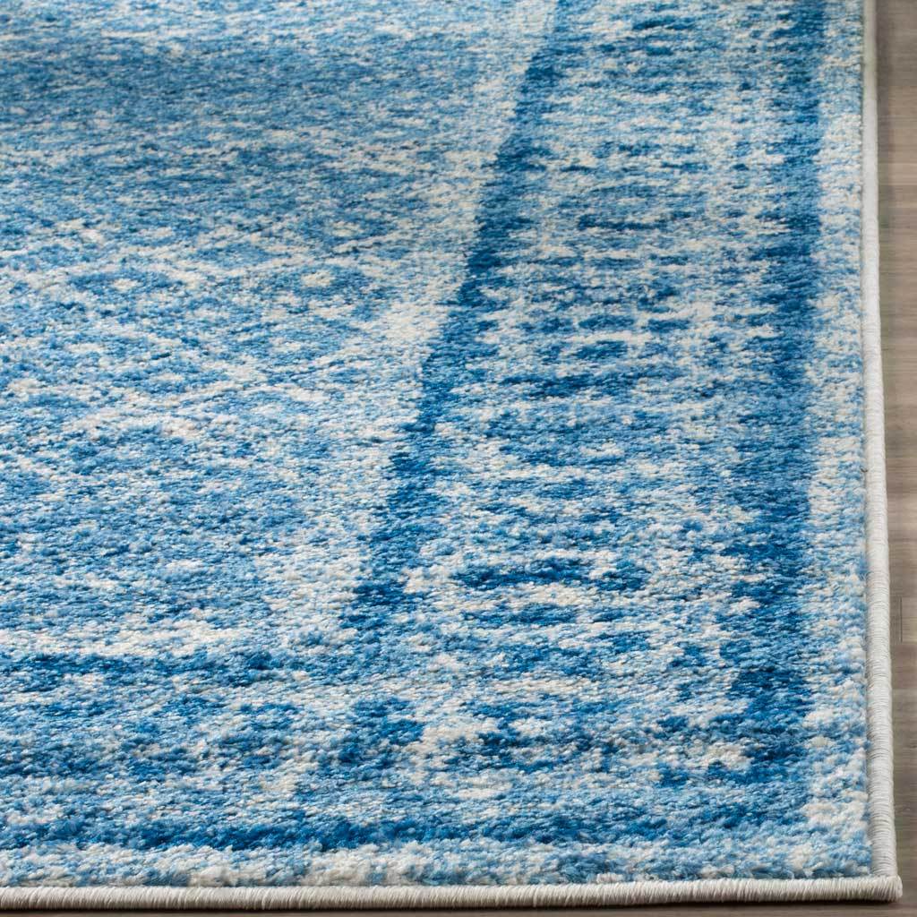 Variegated blue pile and neatly bound edges add depth to the ornamental border