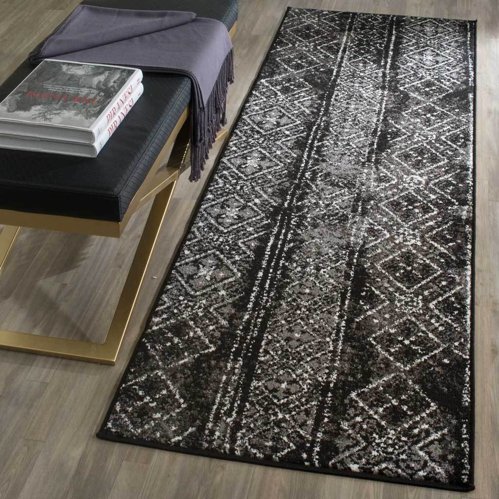 Black and silver runner brings a distressed geometric pattern to wood floors beside a bench.