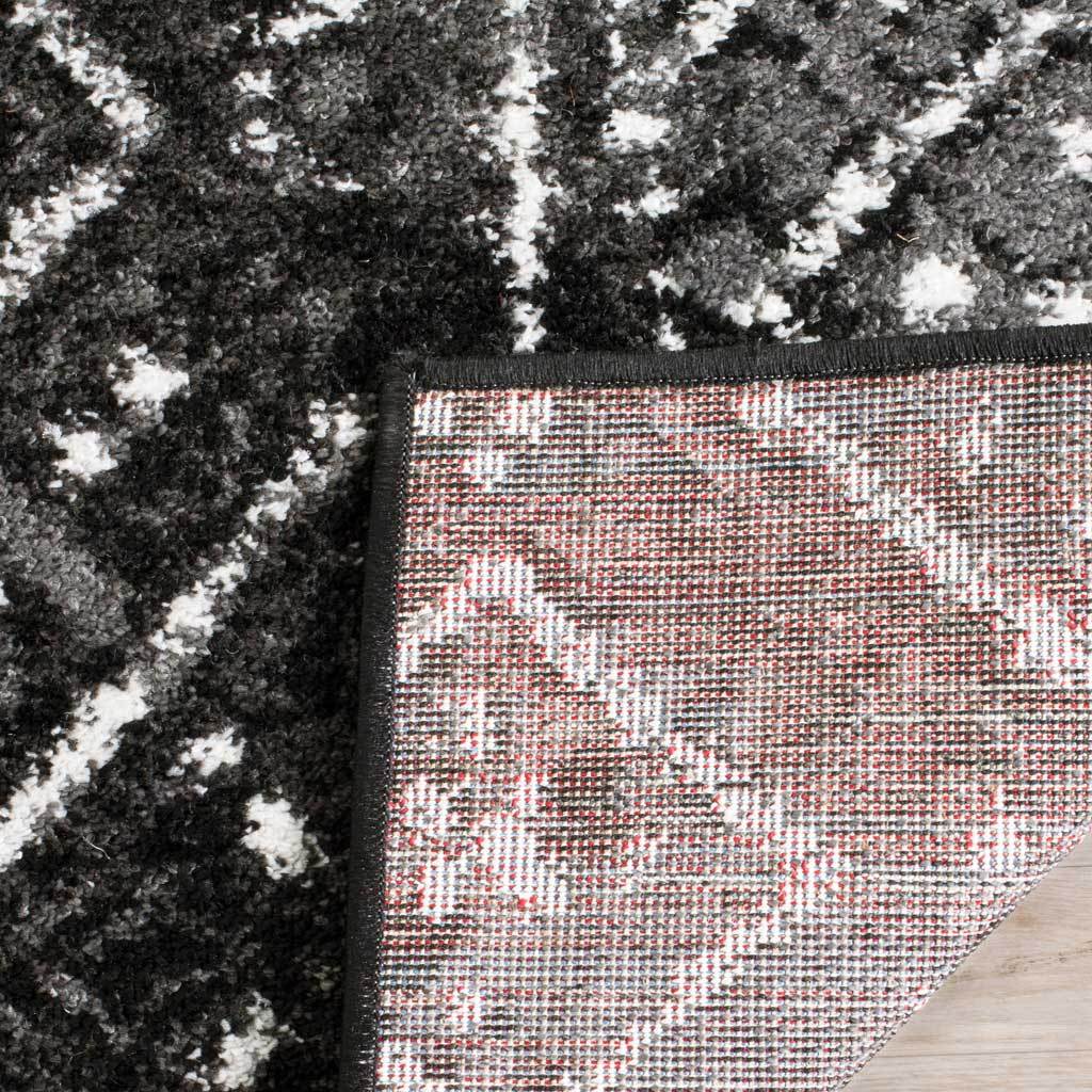 A woven backing and bound edge complement the black and silver patterned pile