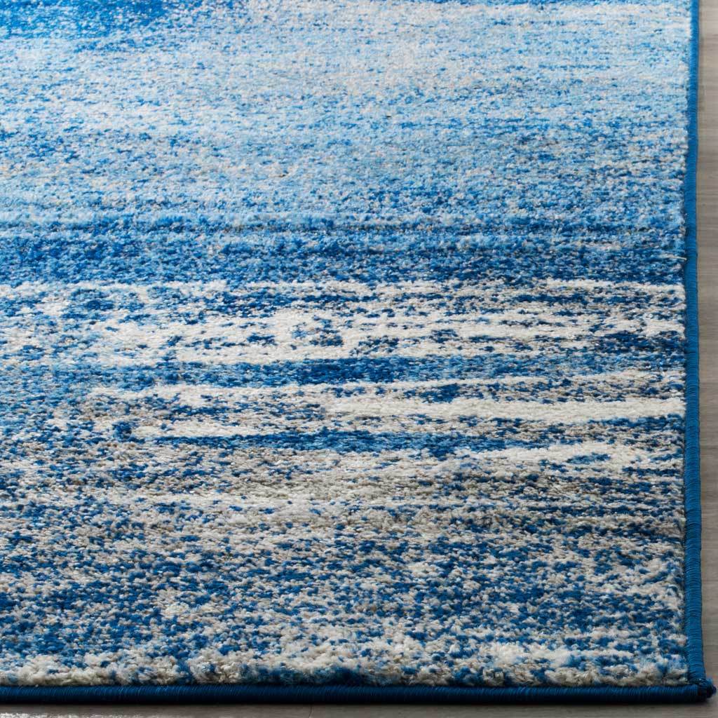 Textured blue and silver pile meets neatly bound edges at the rug's corner