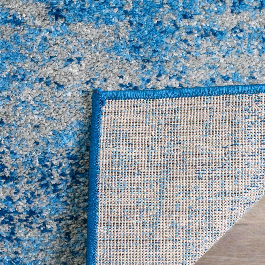 Woven backing contrasts with the silver and blue pile and its blue bound edge