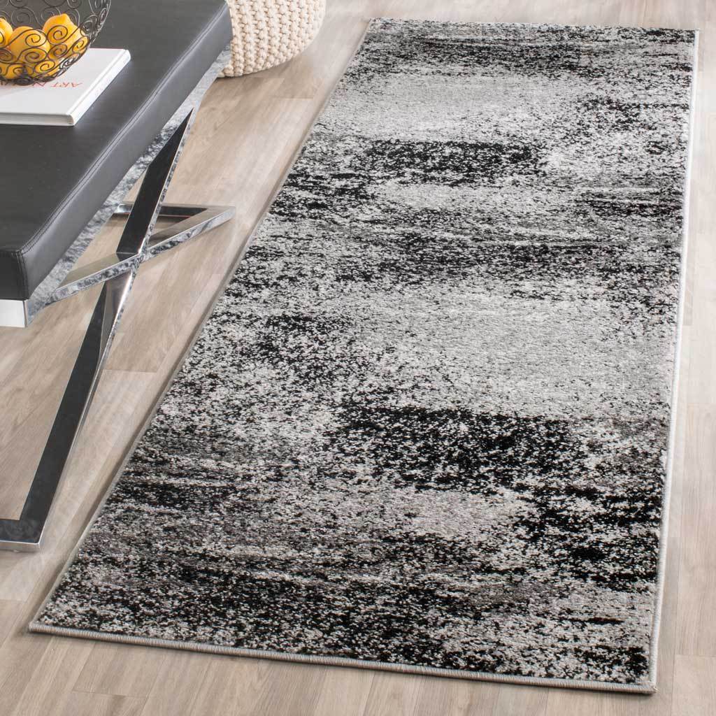 A silver and charcoal runner adds abstract texture beside streamlined furnishings