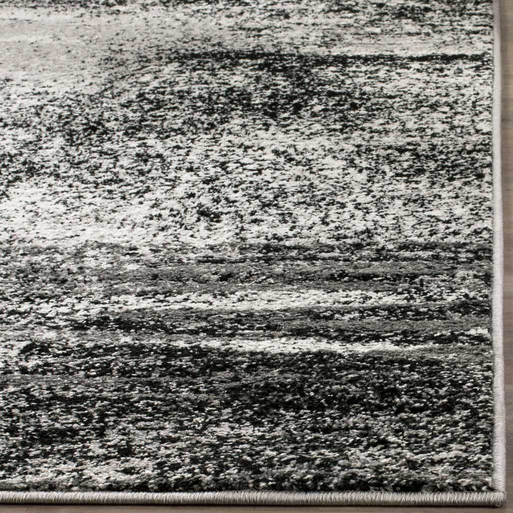 Dense charcoal and silver rug pile ends in a clean, neutral bound corner