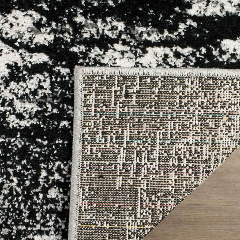 Woven backing and bound edges contrast with the charcoal and ivory patterned pile
