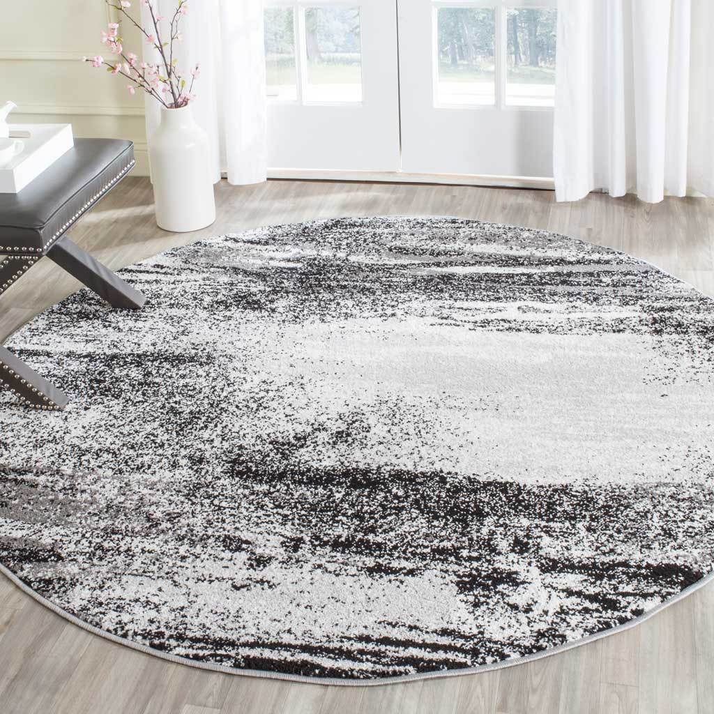 Layered charcoal and silver tones create striking contrast across this round rug