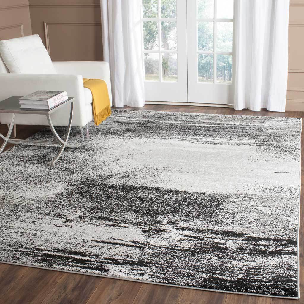 Silver and charcoal rug anchors a bright living room with bold, weathered abstract bands