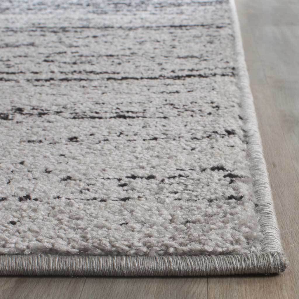 Soft silver pile with scattered black markings meets a neatly bound edge
