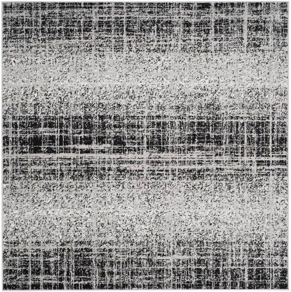 Square silver and black rug with layered dark bands and a distressed, broken-line pattern