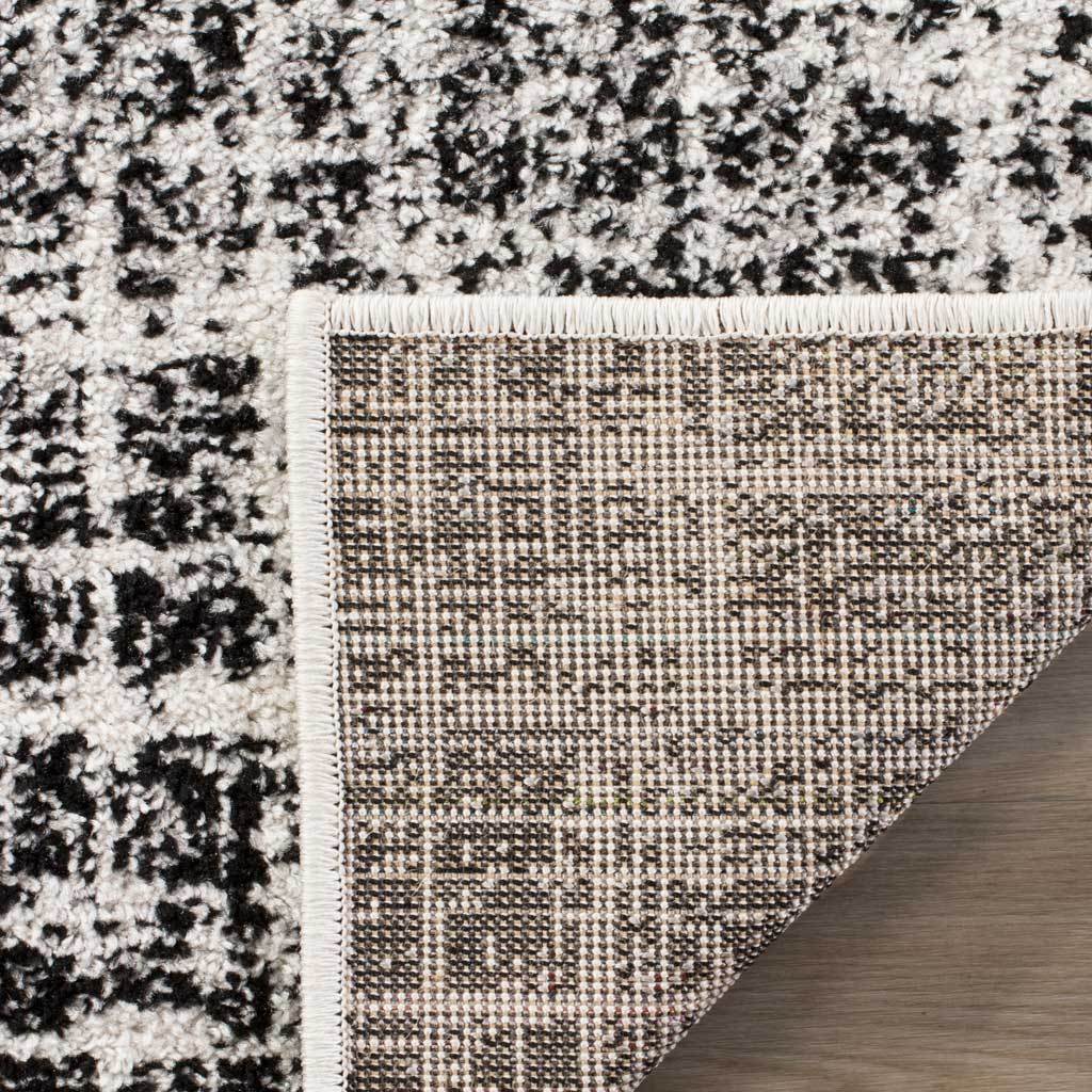 Mottled ivory and black pile pairs with a closely woven jute backing and bound edge