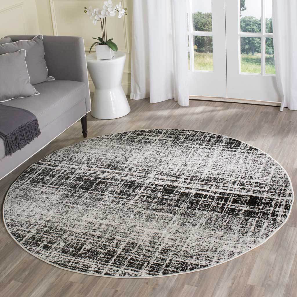 Round ivory and black rug adds bold, distressed pattern to a bright living space