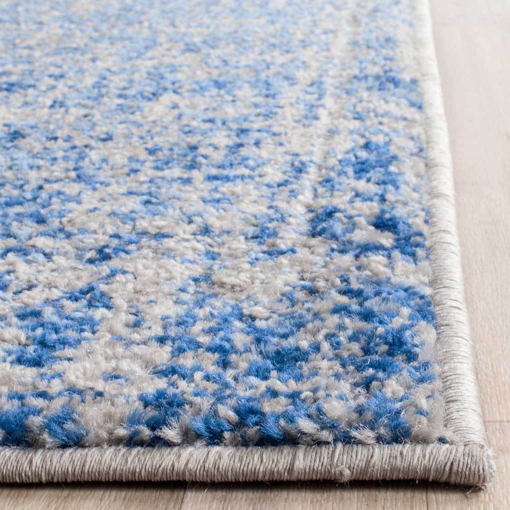 Blue and silver textured pile meets neatly bound edges at the rug's corner
