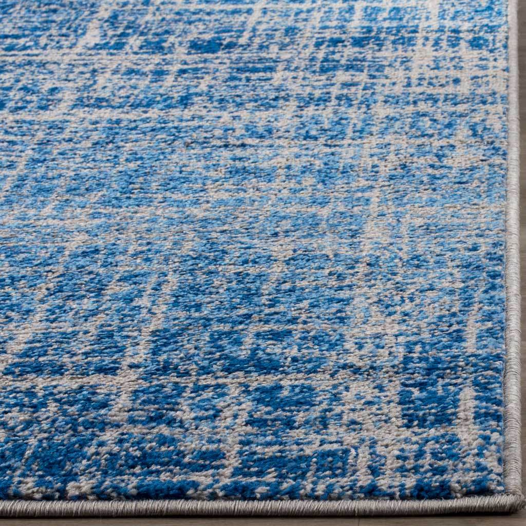 Speckled blue and silver pile meets tightly bound edges along a distressed abstract rug