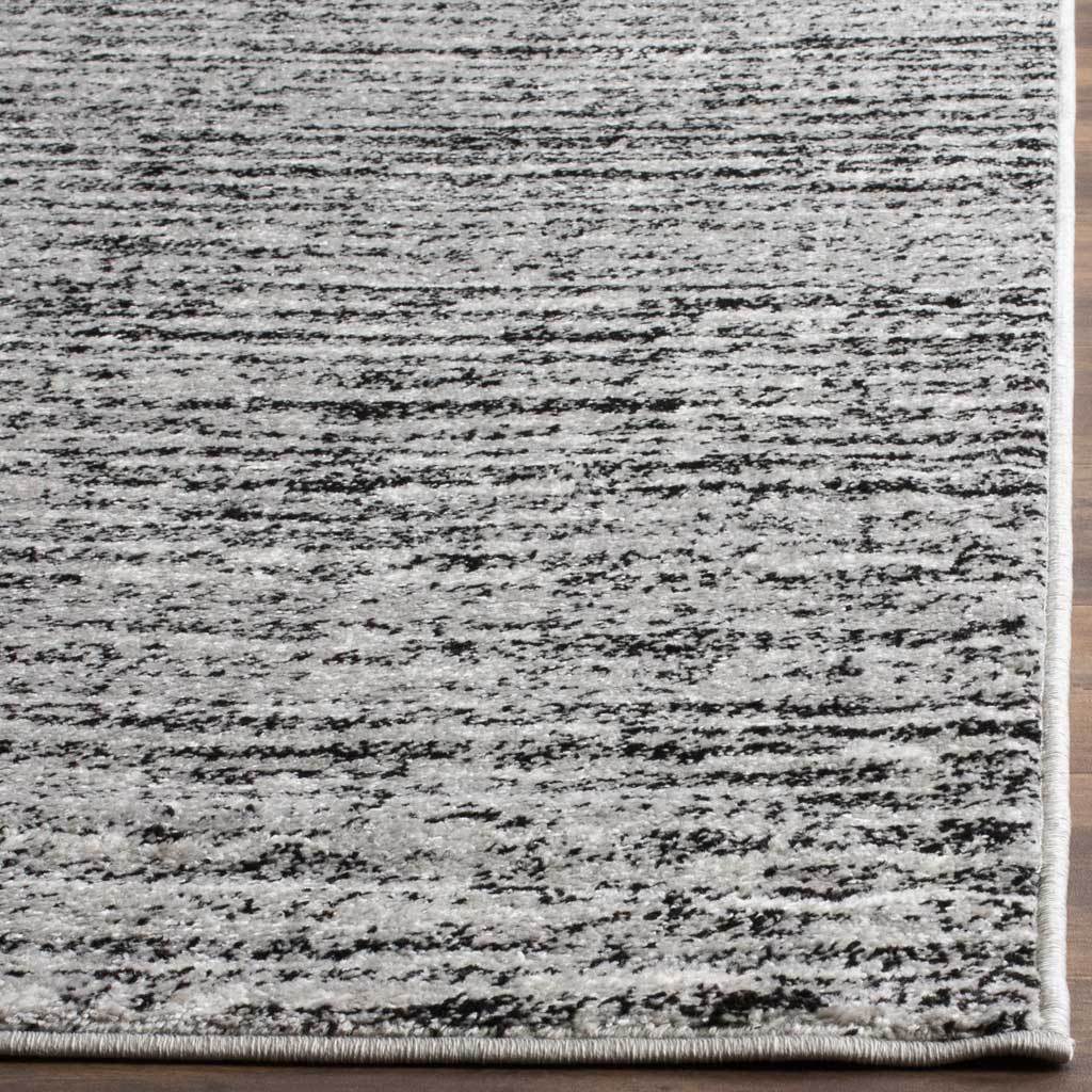 Black and silver abstract stripes meet a smooth bound hem on this textured area rug