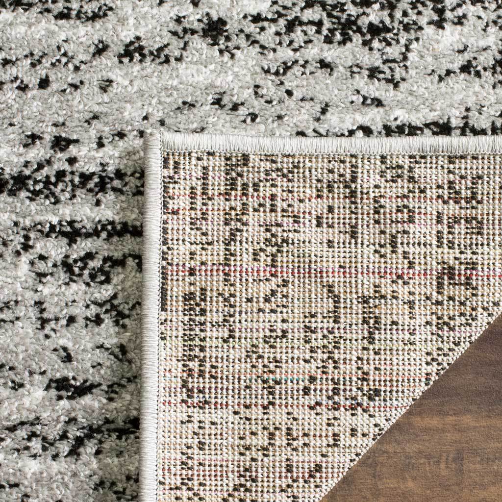 Woven backing and neat edge binding complement the black and silver textured pile