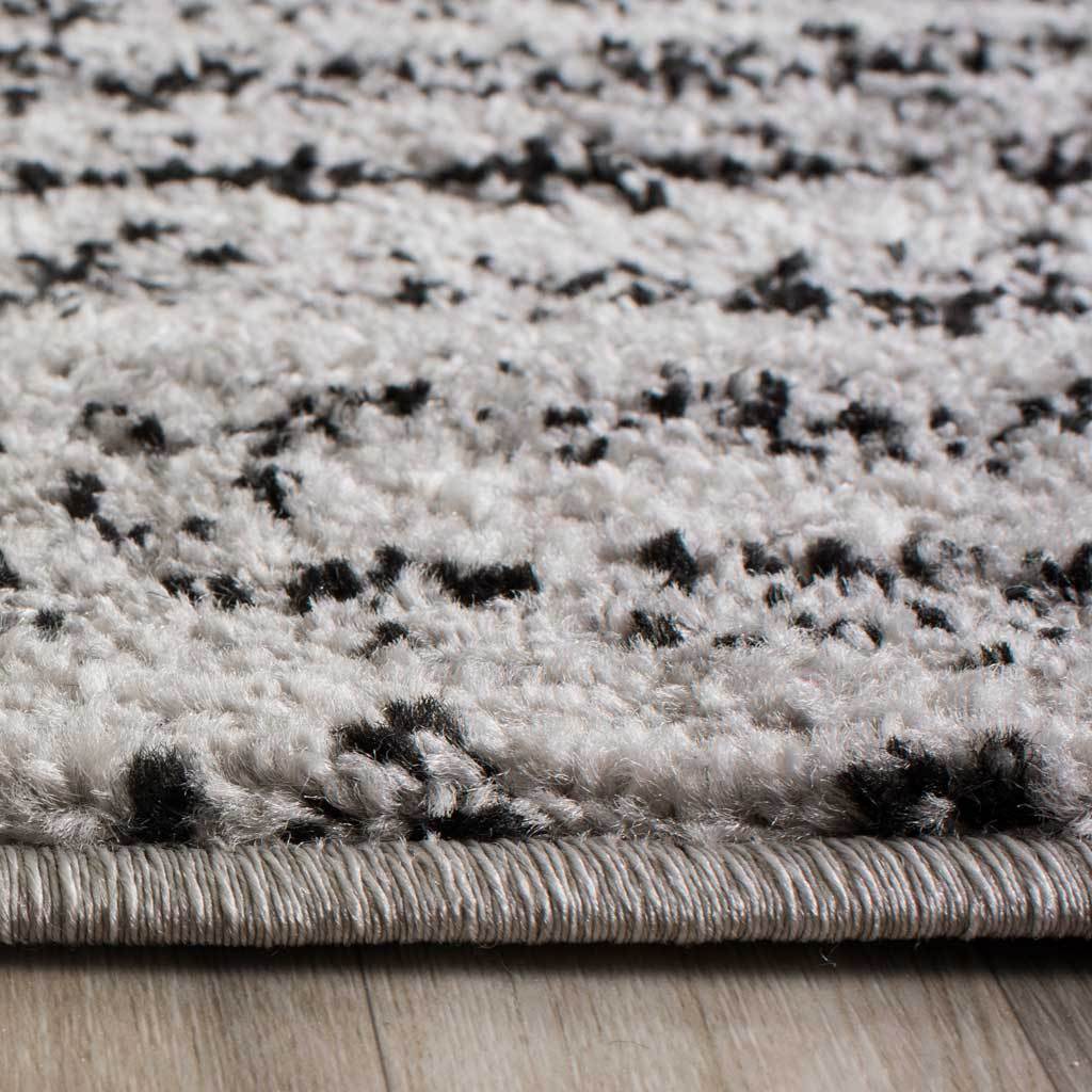 Black and silver flecks mingle across a textured pile with a neatly bound edge