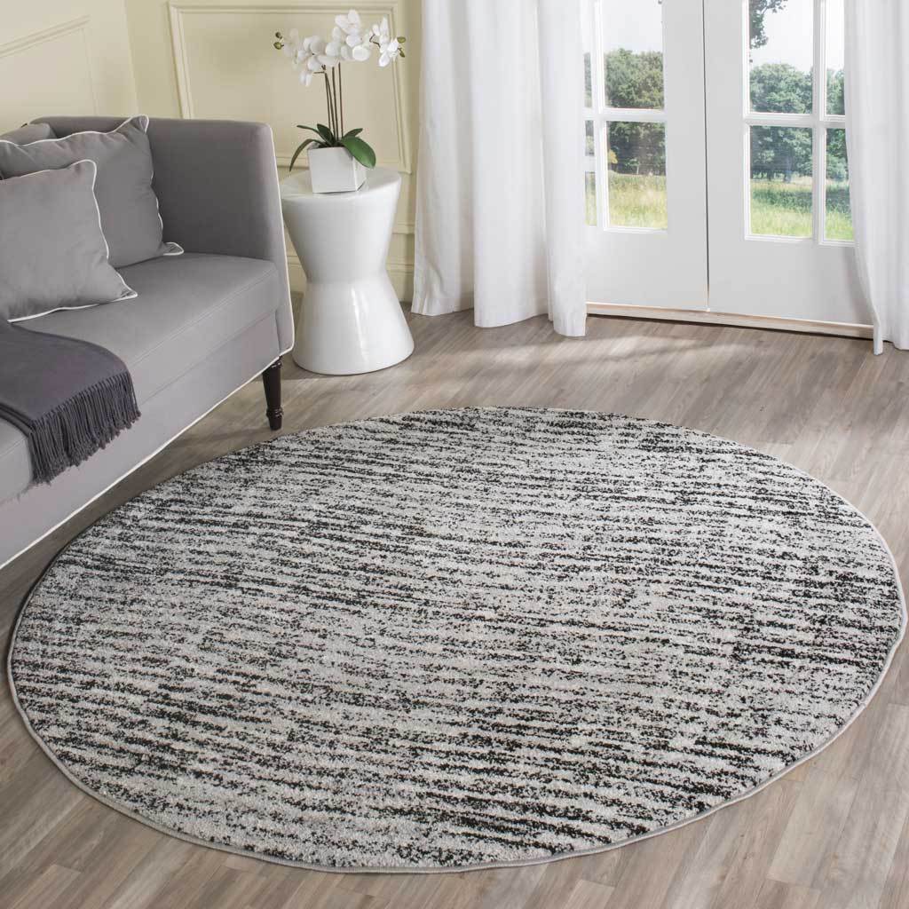 Black and silver round rug adds graphic texture to a bright, neutral living room
