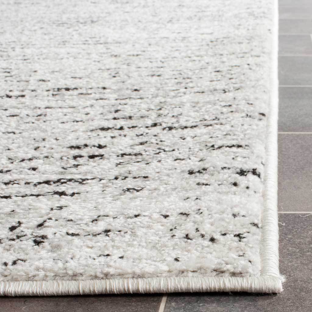 Soft ivory and silver fibers frame a neatly bound edge on this runner rug