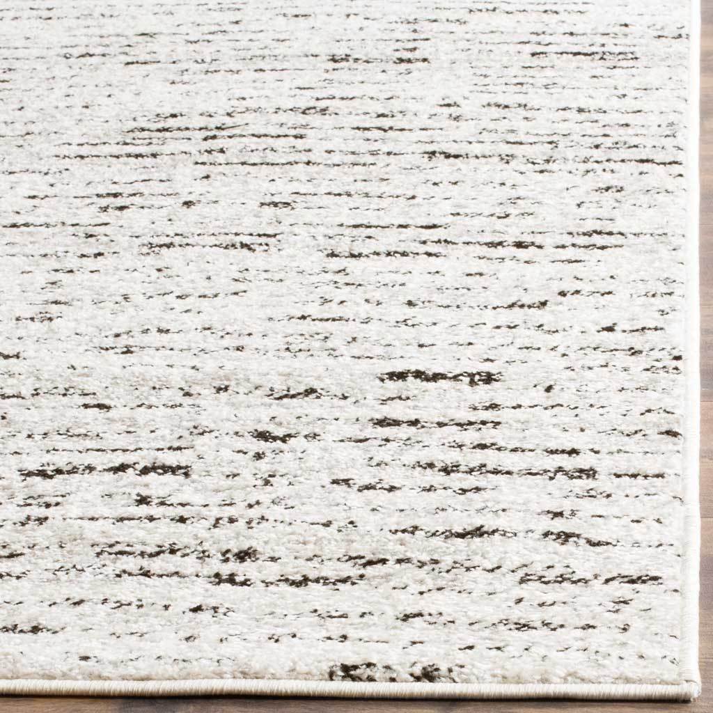 Light ivory pile and fine silver-gray streaks meet a clean, bound rug edge
