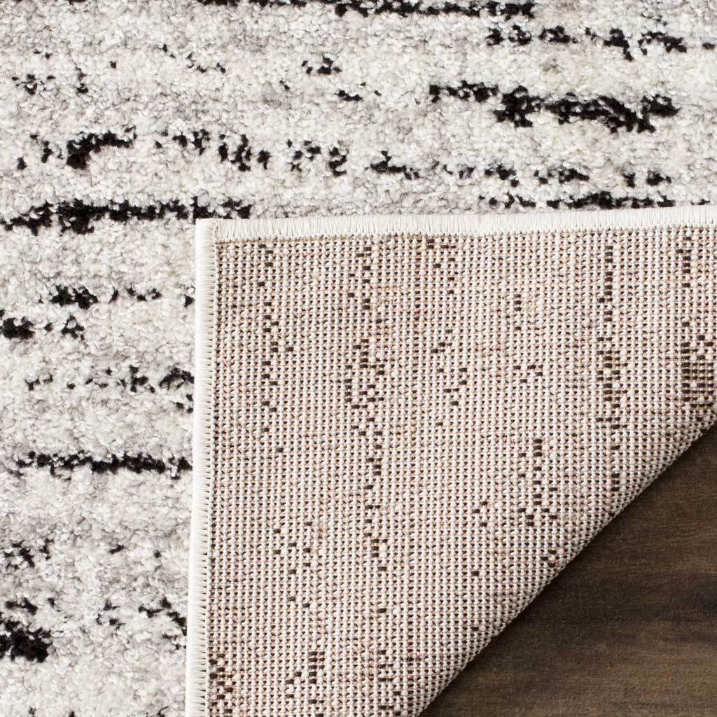 Woven backing and wrapped edges support the ivory rug's softly striped pile